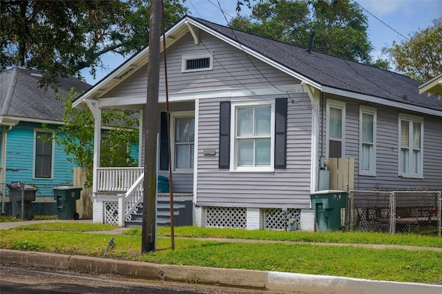 bungalow-style house featuring fence, a porch, and a front lawn