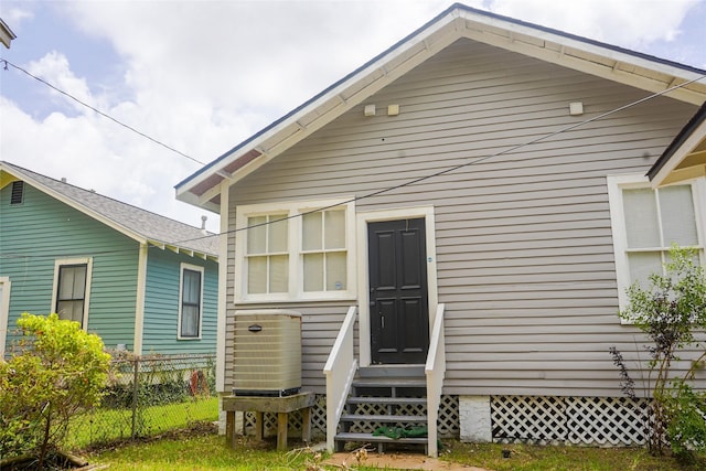 rear view of house featuring entry steps, fence, and cooling unit