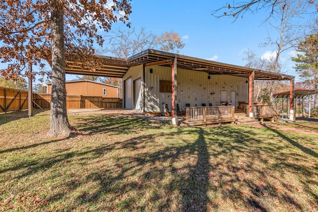 rear view of house featuring a deck, a lawn, and a garage