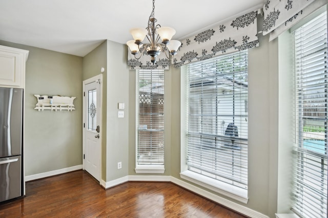 unfurnished dining area featuring a notable chandelier, a healthy amount of sunlight, and dark hardwood / wood-style floors