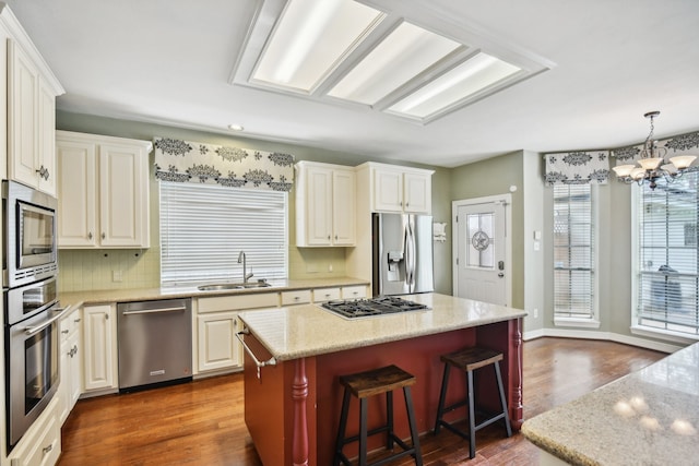 kitchen featuring appliances with stainless steel finishes, tasteful backsplash, a kitchen island, dark hardwood / wood-style floors, and a chandelier