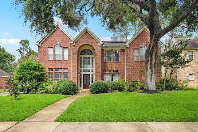 view of front of property featuring solar panels and a front yard