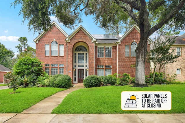 view of front of property featuring a front lawn and solar panels