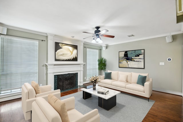 living room featuring dark wood-type flooring, ornamental molding, a high end fireplace, and ceiling fan