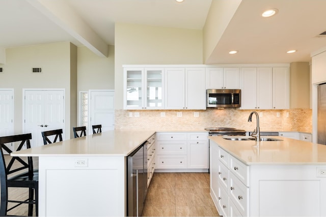 kitchen with white cabinetry, sink, a breakfast bar area, and backsplash