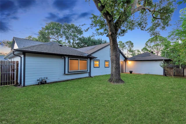 back house at dusk featuring a yard