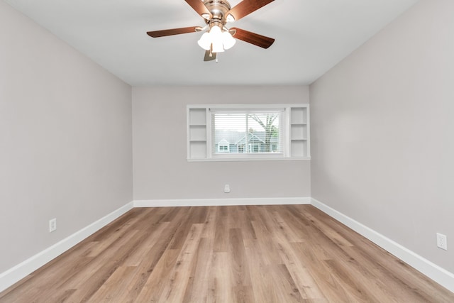 empty room featuring built in features, light wood-type flooring, and ceiling fan