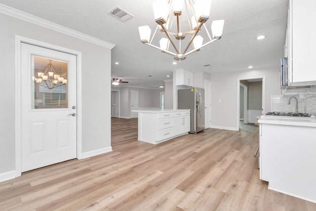 kitchen with decorative backsplash, light hardwood / wood-style flooring, stainless steel appliances, and ceiling fan with notable chandelier