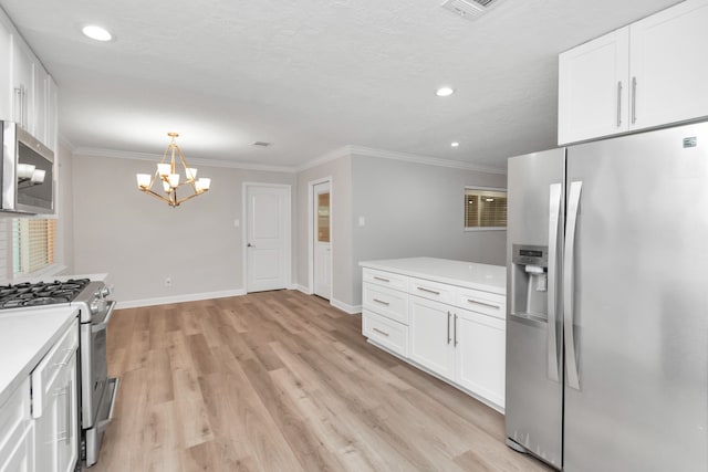 kitchen featuring light wood-type flooring, stainless steel appliances, ornamental molding, and white cabinets