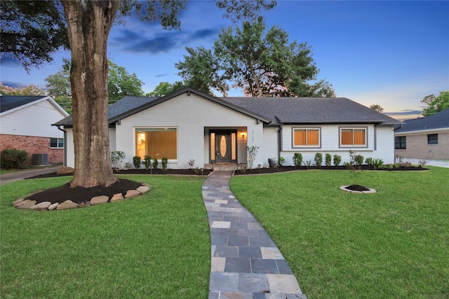 view of front of property with central AC and a yard