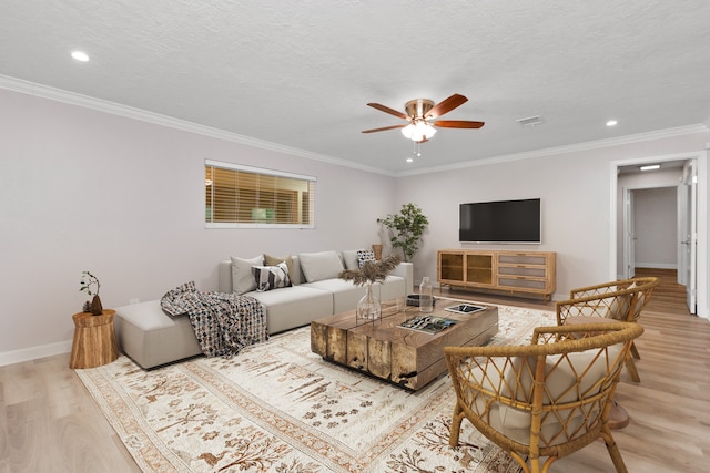 living room with ornamental molding, a textured ceiling, ceiling fan, and light wood-type flooring