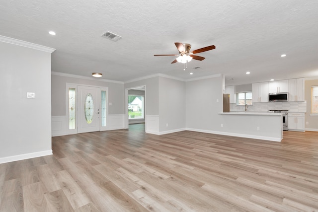 unfurnished living room featuring ceiling fan, ornamental molding, sink, light hardwood / wood-style floors, and a textured ceiling