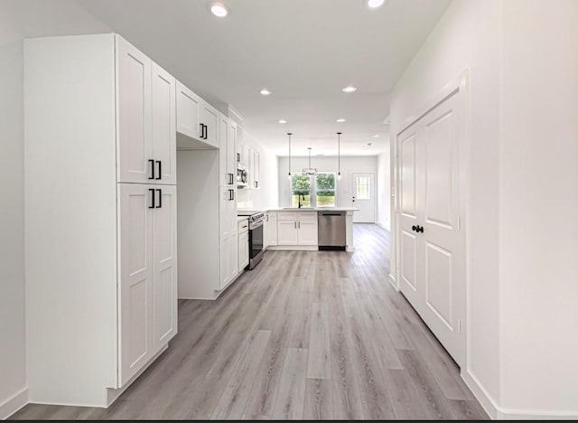 kitchen featuring appliances with stainless steel finishes, white cabinets, light countertops, and pendant lighting