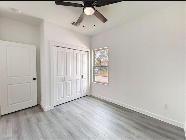 unfurnished bedroom featuring visible vents, baseboards, light wood-style flooring, ceiling fan, and a closet