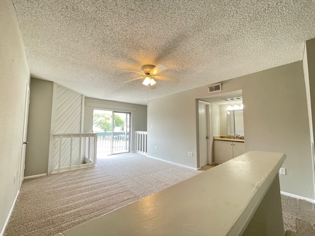 interior space featuring a textured ceiling, carpet floors, and ceiling fan