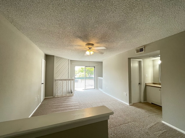 carpeted spare room featuring a textured ceiling and ceiling fan