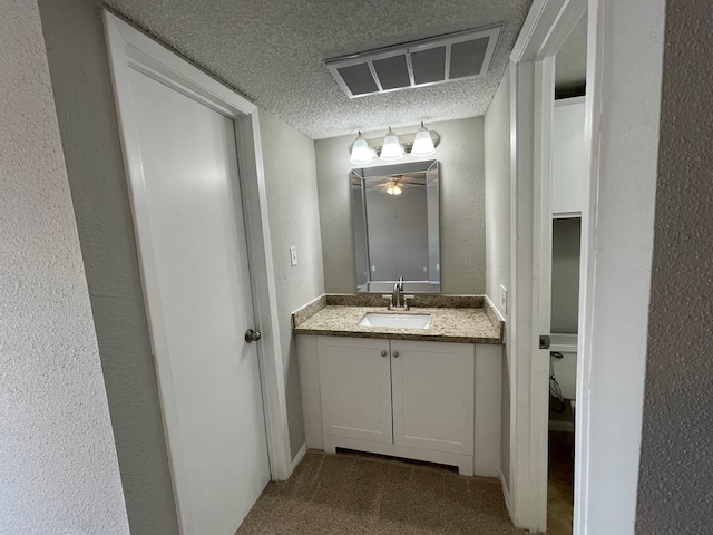 bathroom featuring ceiling fan, toilet, vanity, and a textured ceiling