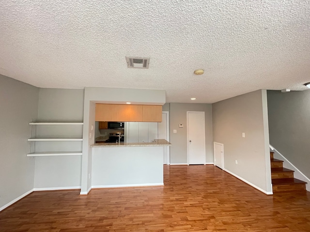 unfurnished living room with a textured ceiling and hardwood / wood-style flooring