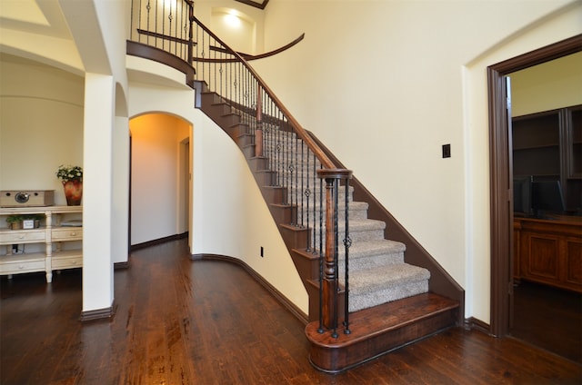 stairway featuring a towering ceiling and hardwood / wood-style floors