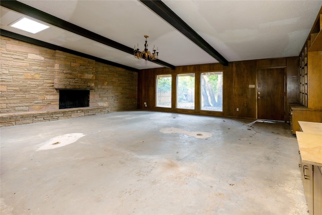 unfurnished living room with a stone fireplace, wood walls, vaulted ceiling with beams, and concrete flooring