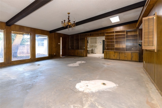 unfurnished living room with concrete floors, wood walls, lofted ceiling with beams, and a notable chandelier