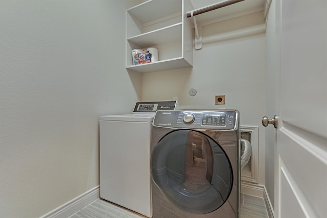 clothes washing area with washing machine and dryer and light hardwood / wood-style flooring