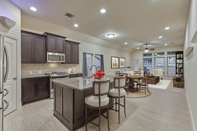 kitchen with ceiling fan, sink, light stone countertops, appliances with stainless steel finishes, and backsplash