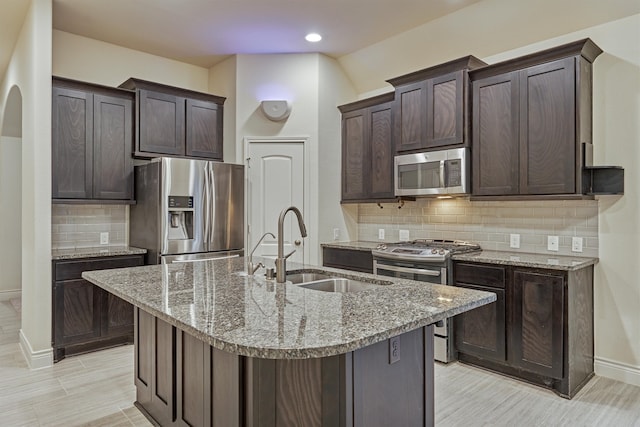 kitchen with tasteful backsplash, an island with sink, and stainless steel appliances