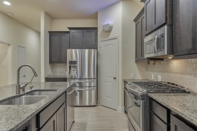 kitchen with sink, light stone countertops, backsplash, and stainless steel appliances