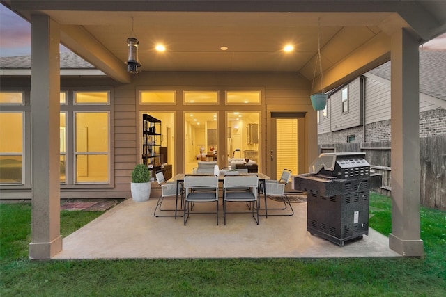 patio terrace at dusk with a lawn, french doors, and grilling area