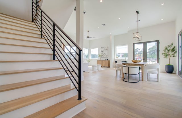 stairs with hardwood / wood-style flooring, a towering ceiling, and french doors