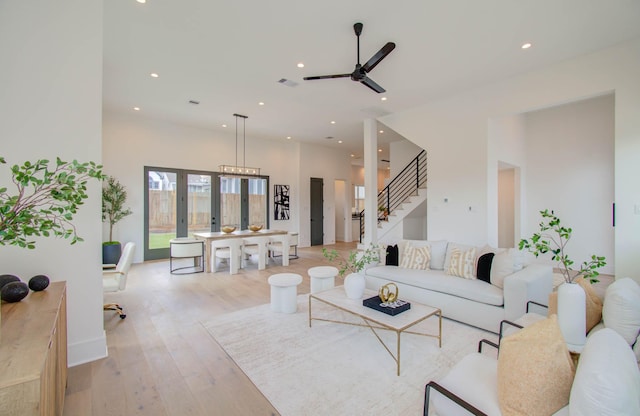 living room with ceiling fan with notable chandelier and light hardwood / wood-style flooring