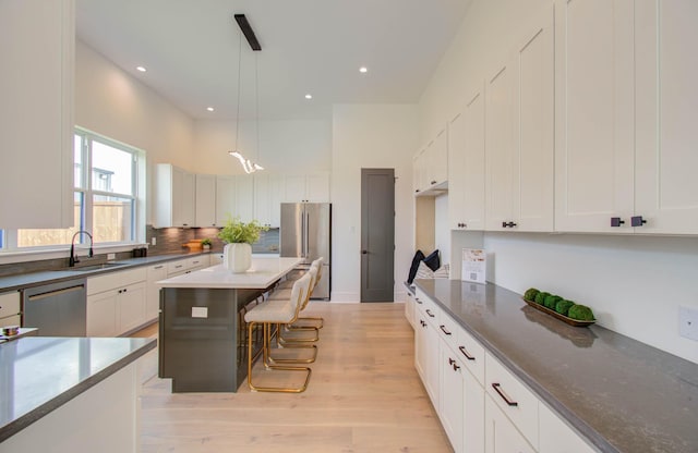 kitchen with sink, white cabinetry, stainless steel appliances, and hanging light fixtures