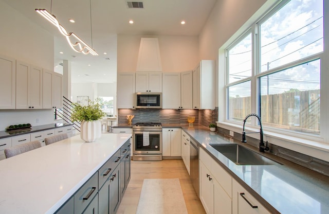 kitchen featuring pendant lighting, gray cabinetry, white cabinets, sink, and stainless steel appliances