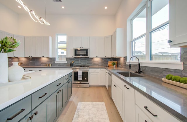 kitchen with sink, stainless steel appliances, pendant lighting, gray cabinets, and white cabinets