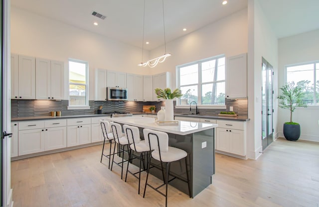 kitchen with a kitchen breakfast bar, white cabinetry, a center island, and a towering ceiling