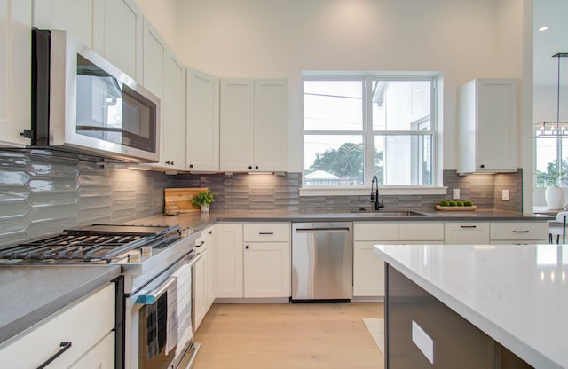 kitchen with white cabinets, backsplash, sink, and appliances with stainless steel finishes