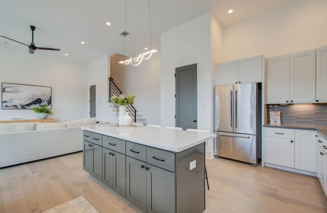 kitchen with high end refrigerator, tasteful backsplash, gray cabinetry, a center island, and hanging light fixtures