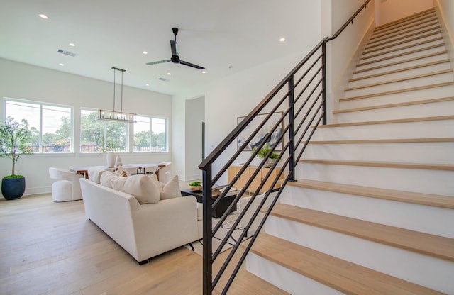 living room featuring ceiling fan with notable chandelier and light hardwood / wood-style flooring