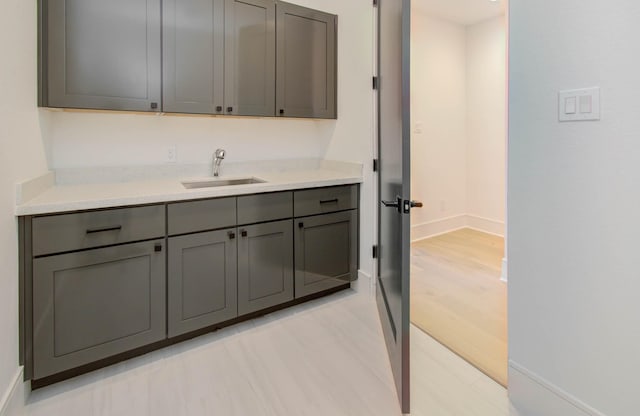 kitchen featuring gray cabinetry, sink, and light hardwood / wood-style floors