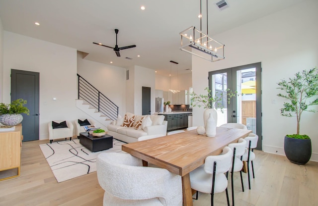 dining area featuring french doors, light hardwood / wood-style flooring, ceiling fan, and a high ceiling