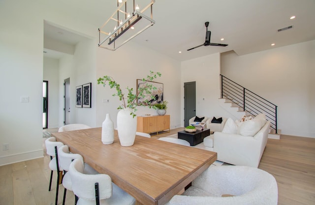 dining space with ceiling fan with notable chandelier and light wood-type flooring