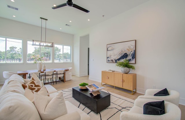 living room with ceiling fan with notable chandelier and light hardwood / wood-style floors