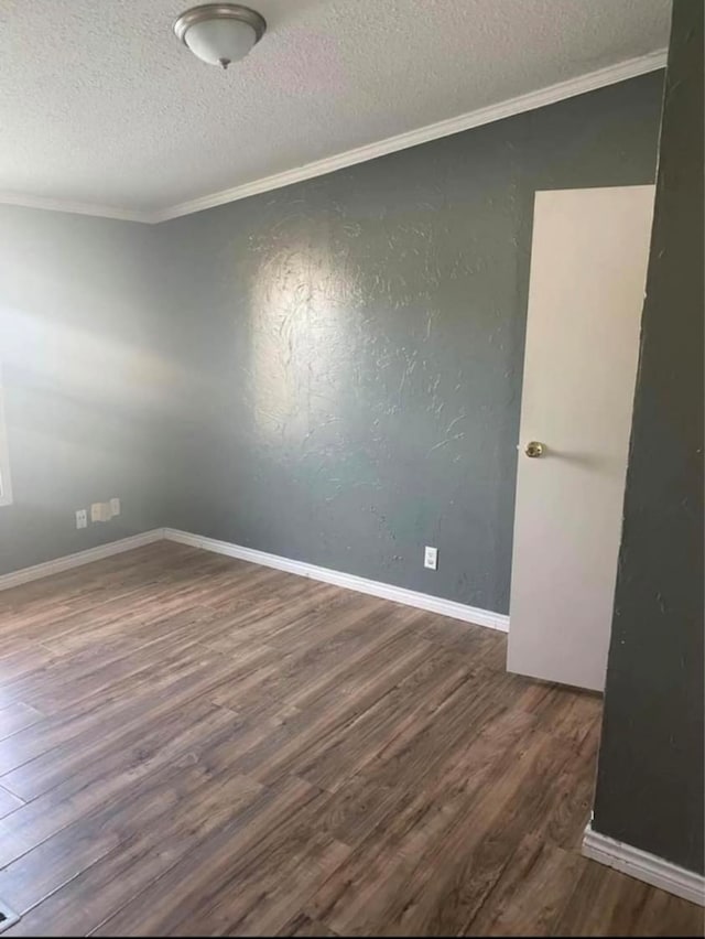 spare room with dark wood-type flooring, a textured ceiling, and ornamental molding