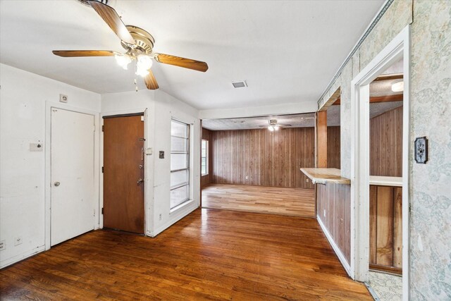 empty room with wooden walls, ceiling fan, and hardwood / wood-style floors