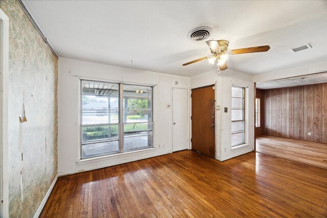 unfurnished room featuring wood walls, ceiling fan, and wood-type flooring