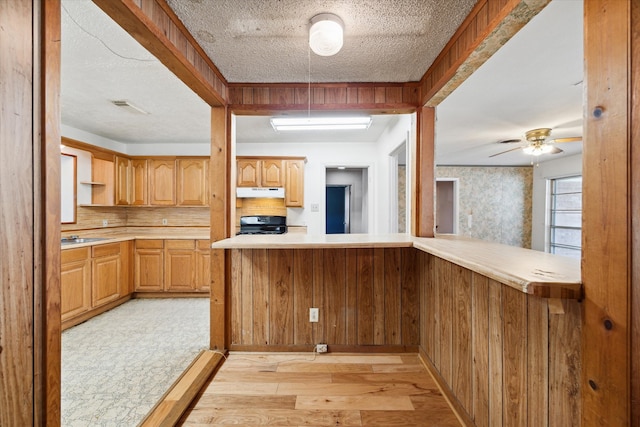 kitchen featuring ceiling fan, kitchen peninsula, light hardwood / wood-style flooring, and a textured ceiling