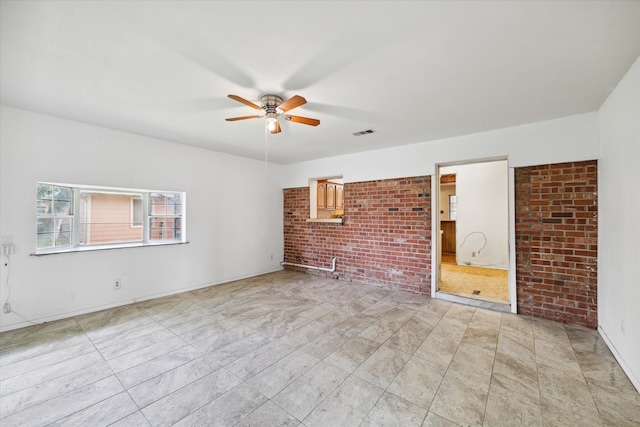 interior space with brick wall, ceiling fan, and light tile patterned floors