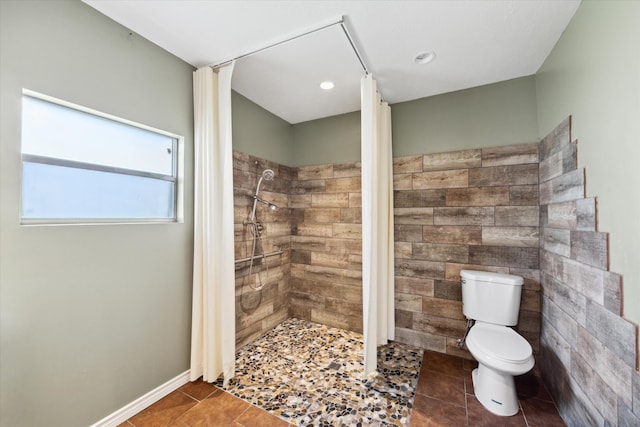 bathroom featuring tile patterned floors, toilet, and a tile shower