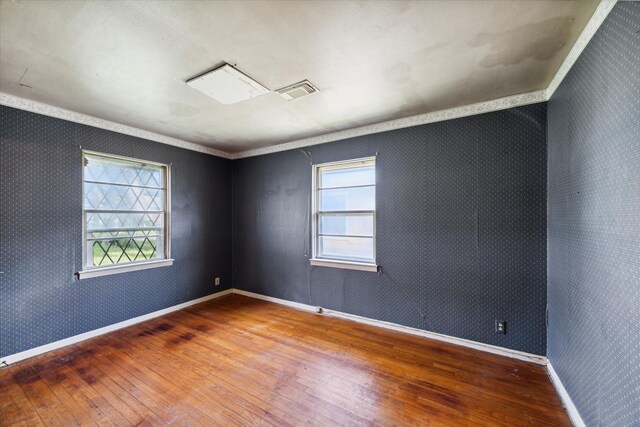 empty room with ornamental molding and hardwood / wood-style floors